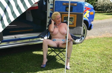 Mature blonde Mary Bitch shows her big tits and pussy outside a B class camper