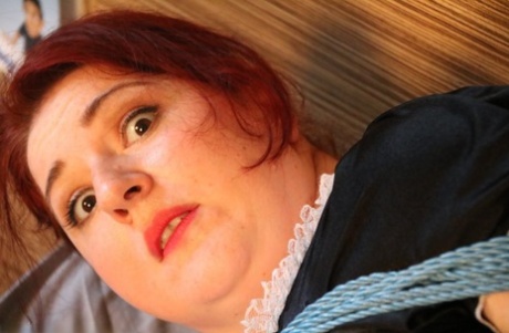 Natural redhead is left tied up on a bed in her maid uniform