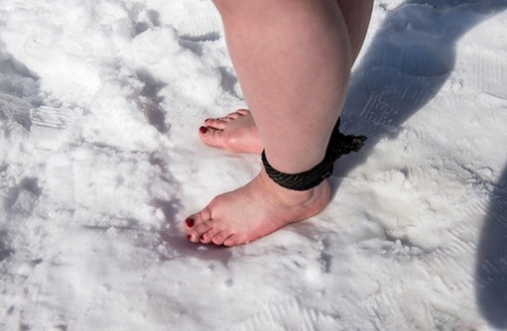 Brunette BBW rids ball gag and ropes while posing nude and barefoot in snow