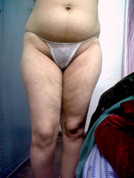 Fat Indian woman hides her face while adorned in a bra and thong