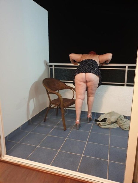 Fat nan with short red hair presses her big boobs and butt up against glass