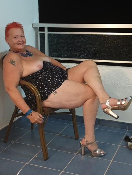 Fat nan with short red hair presses her big boobs and butt up against glass