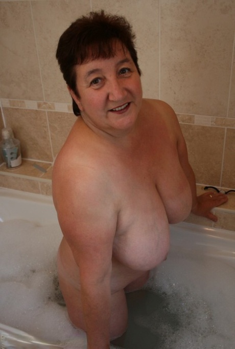 Older redhead Kinky Carol sinks her plump body into a tub of bathwater