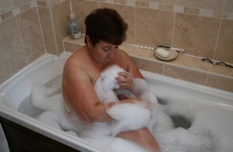 Older redhead Kinky Carol sinks her plump body into a tub of bathwater