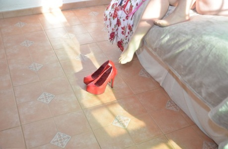 Older blonde Melody removes her high heels while getting naked on a bed