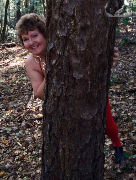 Older amateur Busty Bliss displays her big natural tits while nude in a forest