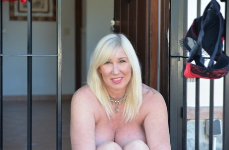 Mature blonde BBW Melody goes topless on a patio in thong underwear