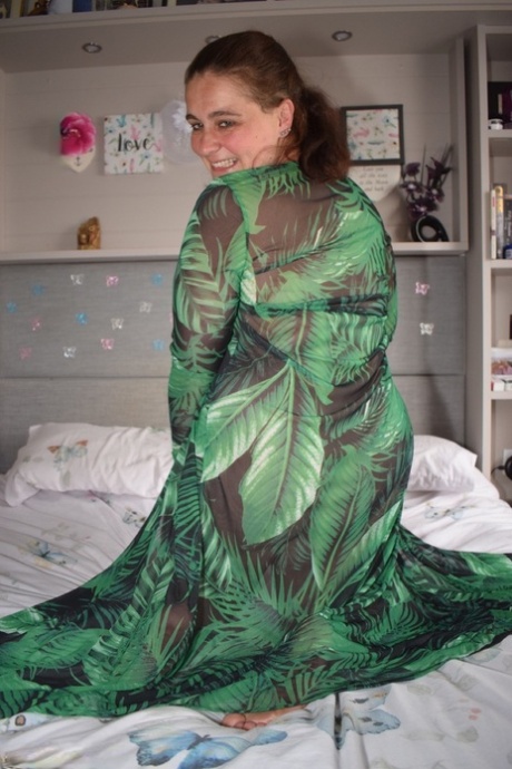 Fat woman exposes herself on a bed while wearing a long dress