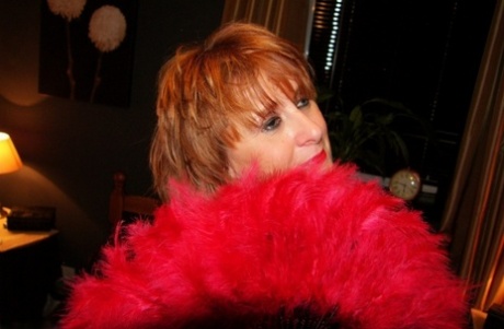 Older redhead shows her tits and twat while draped in a feather boa