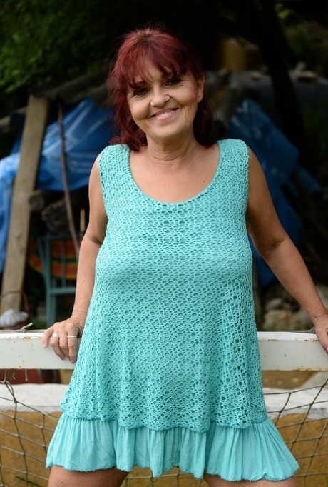 Redhead granny Livia lifts her blue dress up and reveals big natural tits
