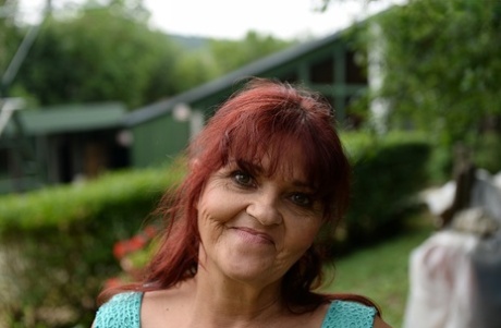 Redhead granny Livia lifts her blue dress up and reveals big natural tits