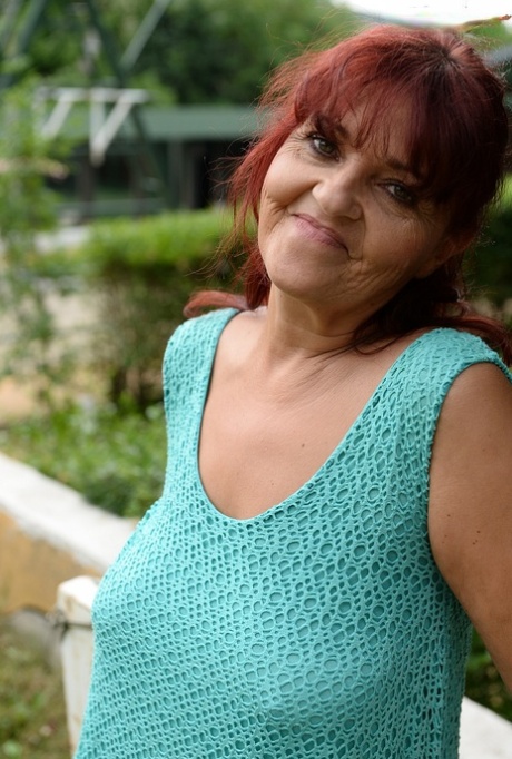 Redhead granny Livia lifts her blue dress up and reveals big natural tits